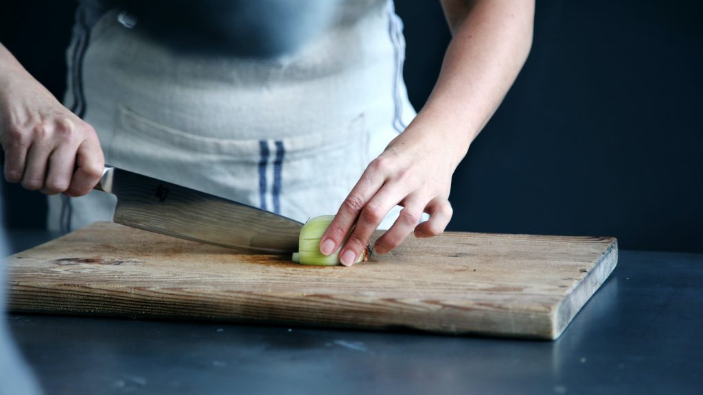 Chef cutting an onion on an onion board