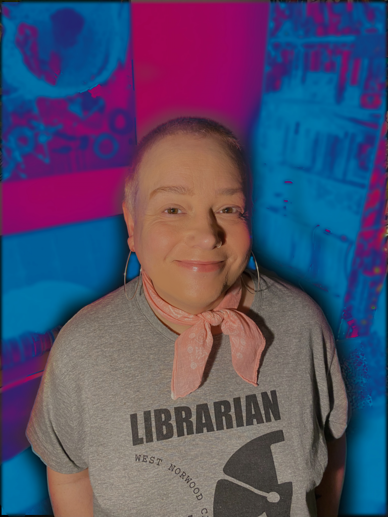 Jaye Ward, looking into the camera with a pick neckerchief and grey t-shirt with "Librarian" on it.