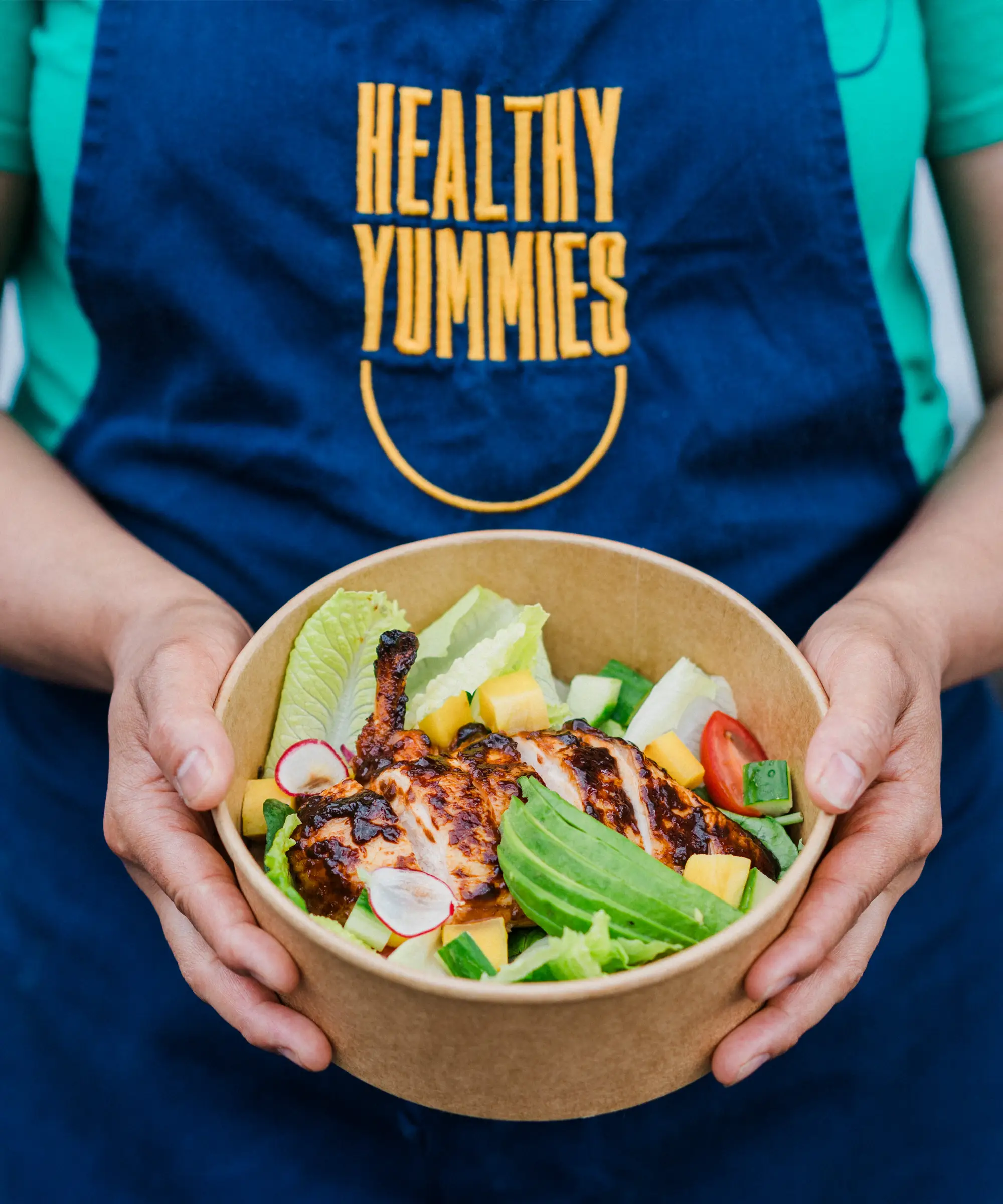 A Yummies team member holding a bowl of chicken salad (photograph).